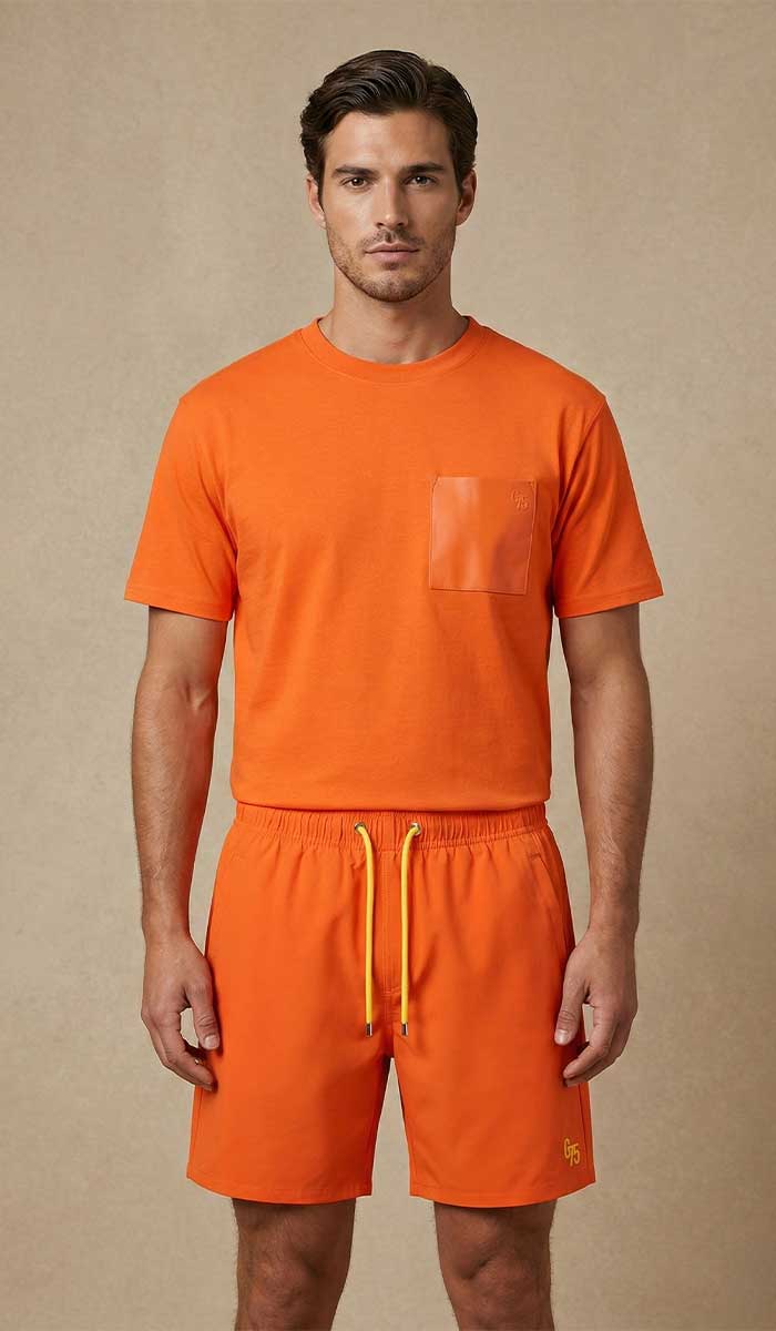 MANNEQUIN HOMME EST VETU DU TEE SHIRT ORANGE ET SHORT DE BAIN ASSORTI POSE DEBOUT FACE A L'OBJECTIF 